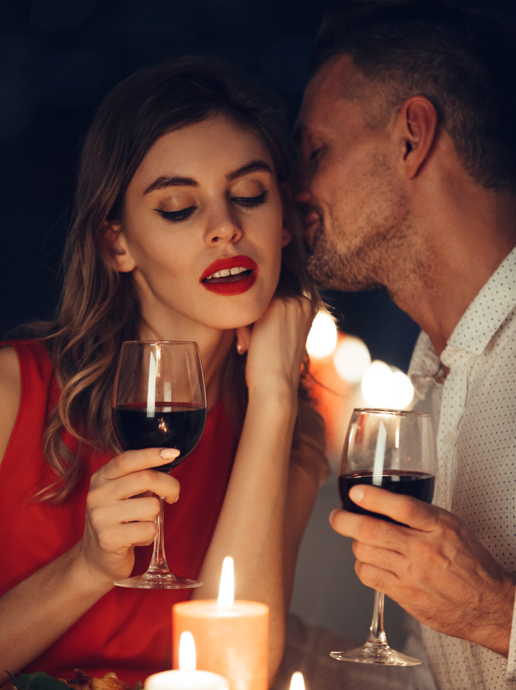 Curious lady in dress red with glass of wine listening her handsome man